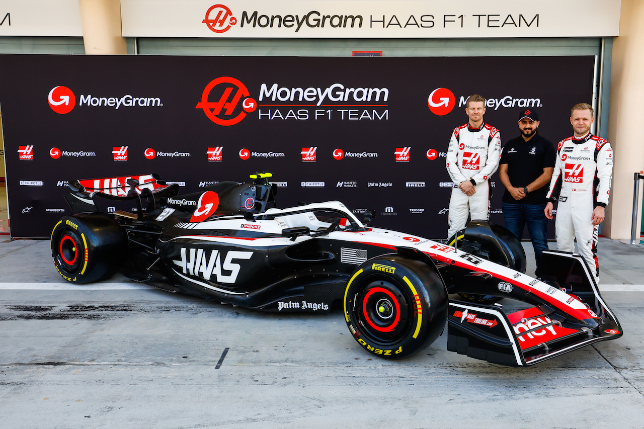 BAHRAIN INTERNATIONAL CIRCUIT, BAHRAIN - FEBRUARY 23: Nico Hulkenberg, Haas F1 Team, a guest and Kevin Magnussen, Haas F1 Team,next to the Haas VF-23 during the Bahrain February Testing at Bahrain International Circuit on Thursday February 23, 2023 in Sakhir, Bahrain. (Photo by Sam Bloxham / LAT Images)